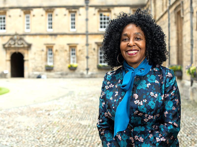 Professor Brenda Stevenson smiles to camera as she stands in one of the quads at St John’s College