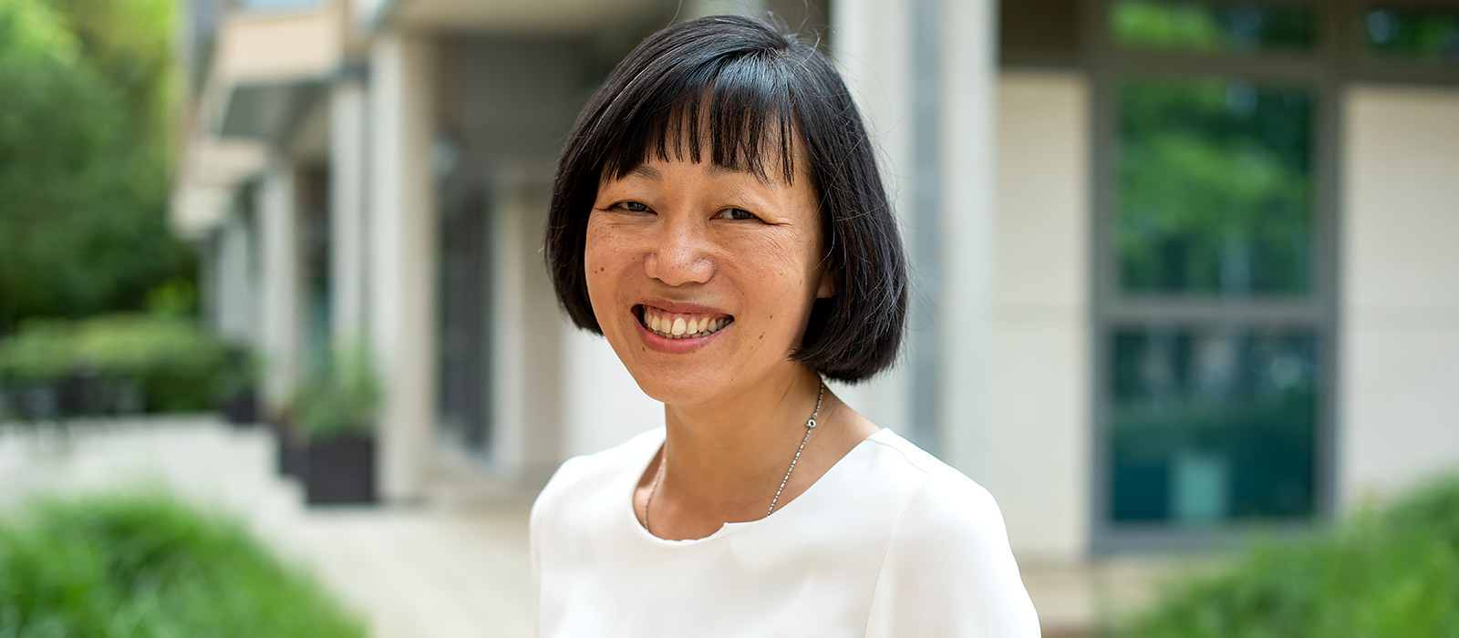 Bo Hu smiling as she stands in the grounds of the University of Oxford China Centre