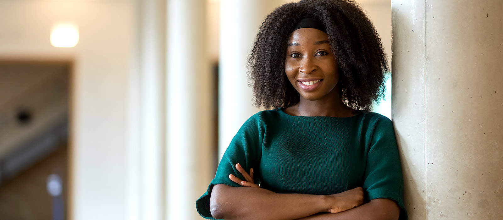 Crystal Chika Okwurionu leans against a pillar in the entrance hall of the Saïd Business School