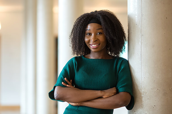 Crystal Chika Okwurionu leans against a pillar in the entrance hall of the Saïd Business School