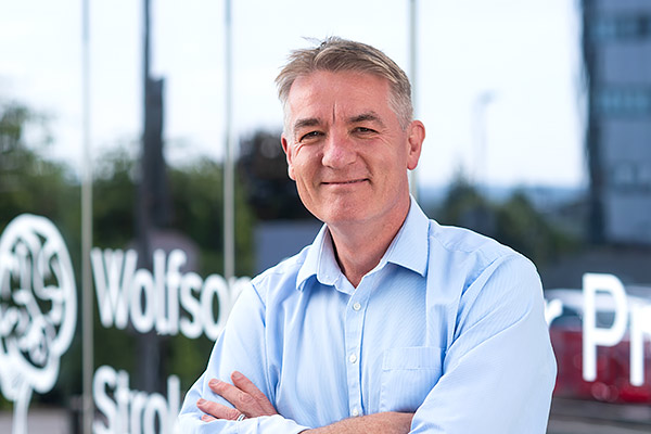 Professor Peter Rothwell smiles as he stands in front of the Wolfson Centre for the Prevention of Stroke and Dementia on the John Radcliffe Hospital site