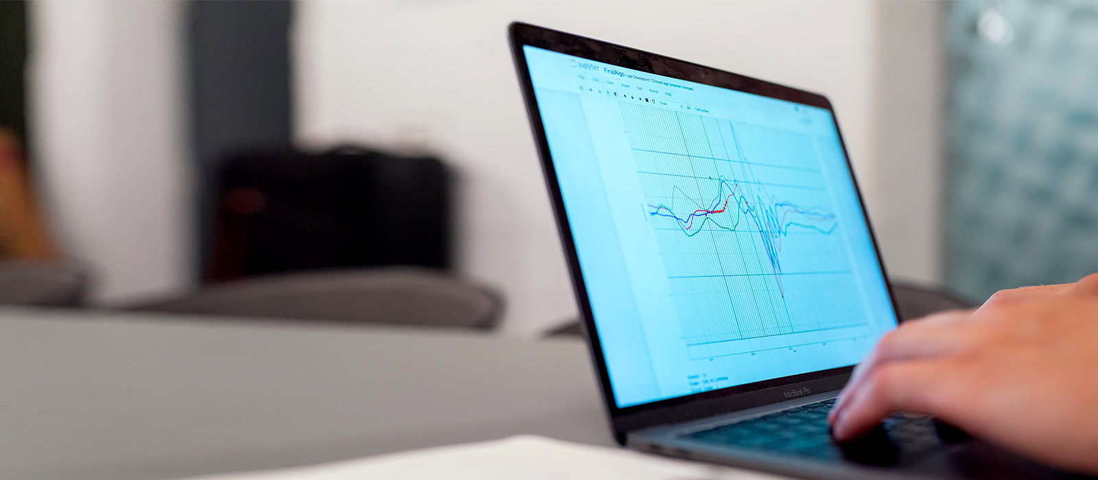 A laptop displays graphs as a person types something on the keyboard