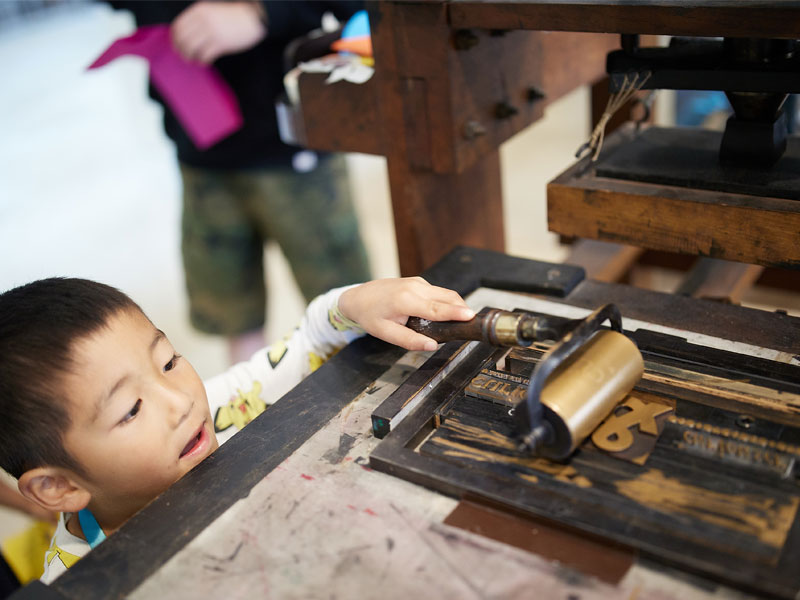 A young visitor tries their hand at printing. Photo by Ian Wallman