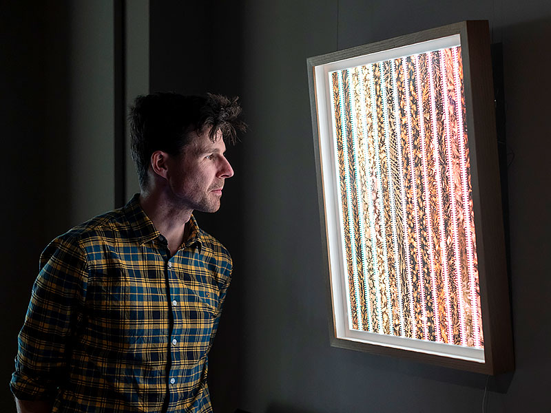 Dr Phillip Roberts looks intently at an illumined display containing film negatives