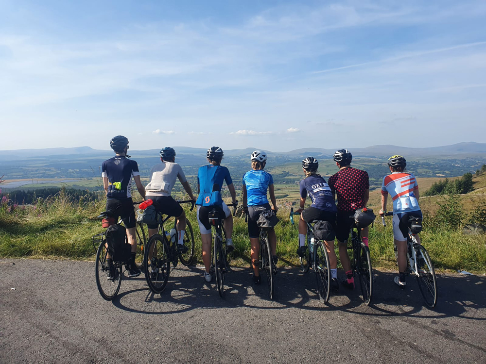 A group of cyclists looking into the distance at the top of a hill