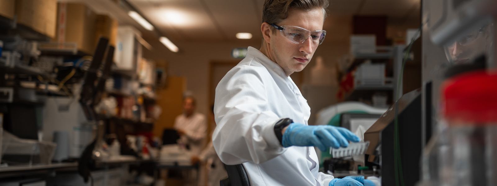 A researcher in a laboratory reaches for a sample
