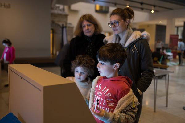 Family interacting with one of the digital displays during the ‘Alice in Typhoidland’ exhibition