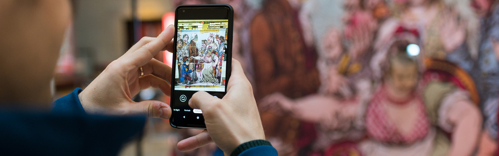 Visitor exploring displays via a phone app during the 'Alice in Typhoidland' exhibition by John Cairns