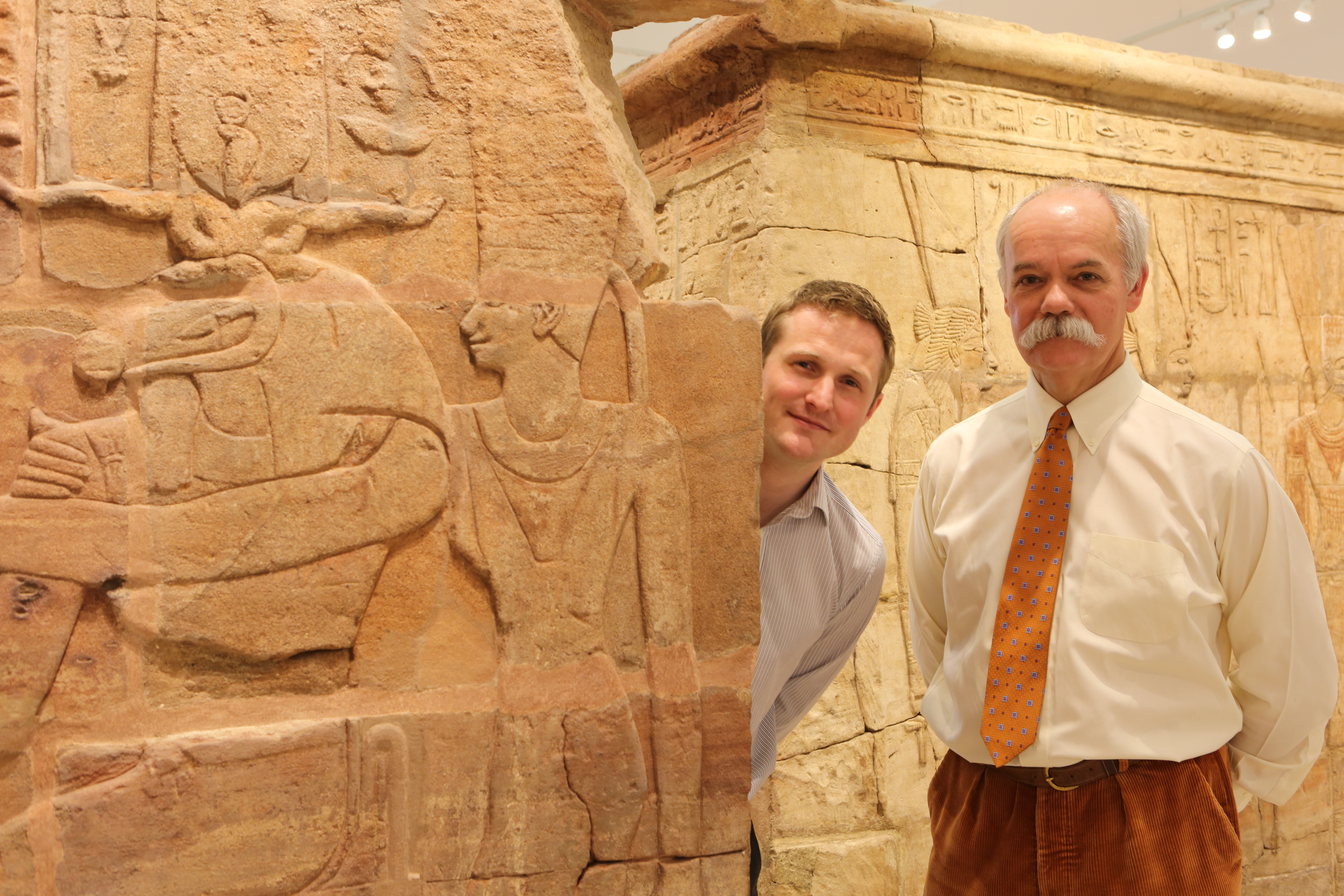 Two persons standing next to an archaeology exhibit