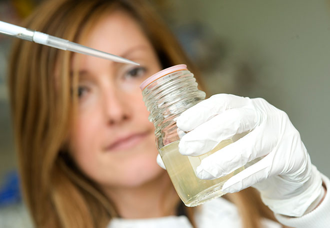 Female researcher holding phial and pipette. Photo Credit: University of Oxford / Rob Judges Photography