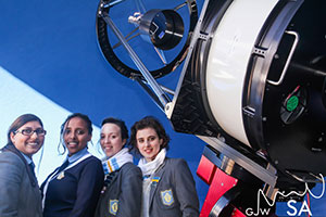 Four students standing next to an Observatory telescope
