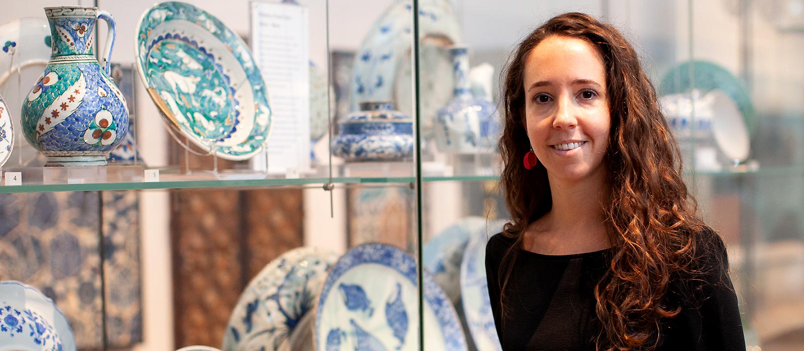 Dr Federica Gigante standing in front of display of Islamic ceramics at the Ashmolean Museum