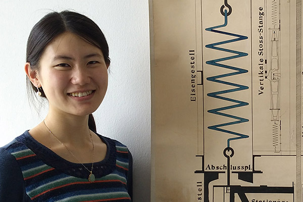 DPhil scholarship student Qi Ou standing next to a design of an early seismometer at the University of Hamburg