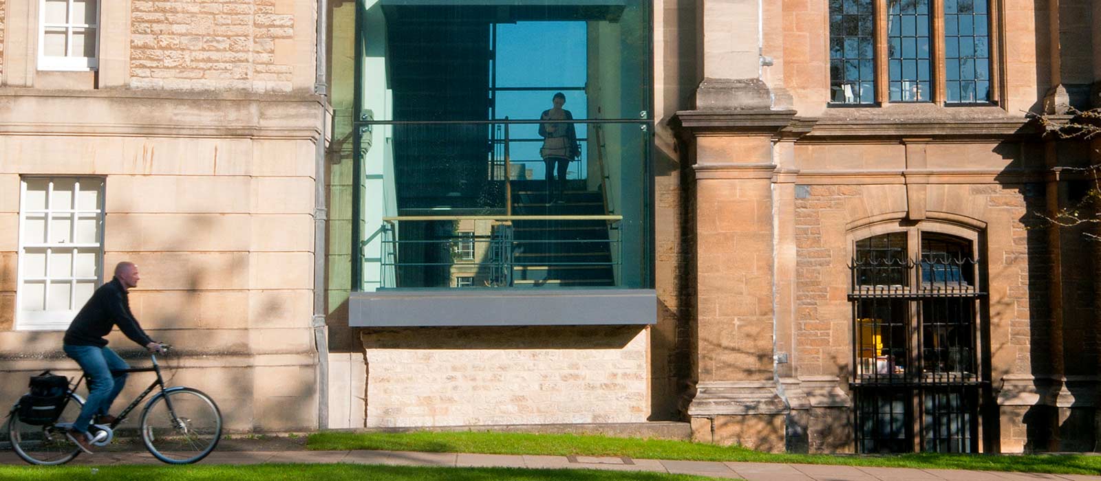 Man cycling on a footpath outside Reuben College in Oxford