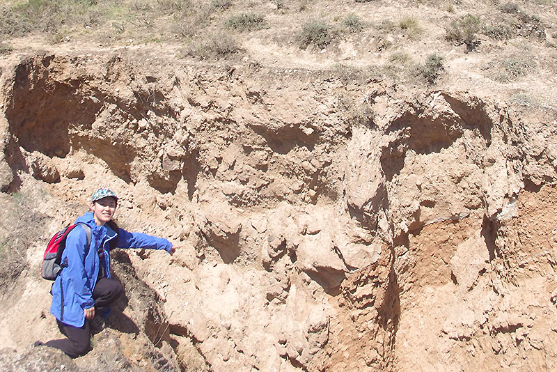 DPhil scholarship student Qi Ou on a field trip in 2018, pointing at a cross-section of the Haiyuan Fault in China