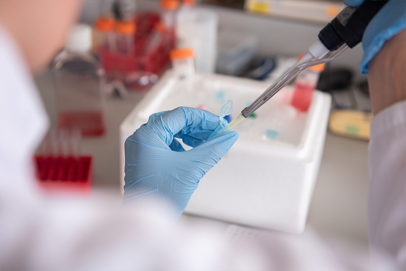 A COVID-19 vaccine researcher pipetting liquid into a receptacle in an Oxford University laboratory