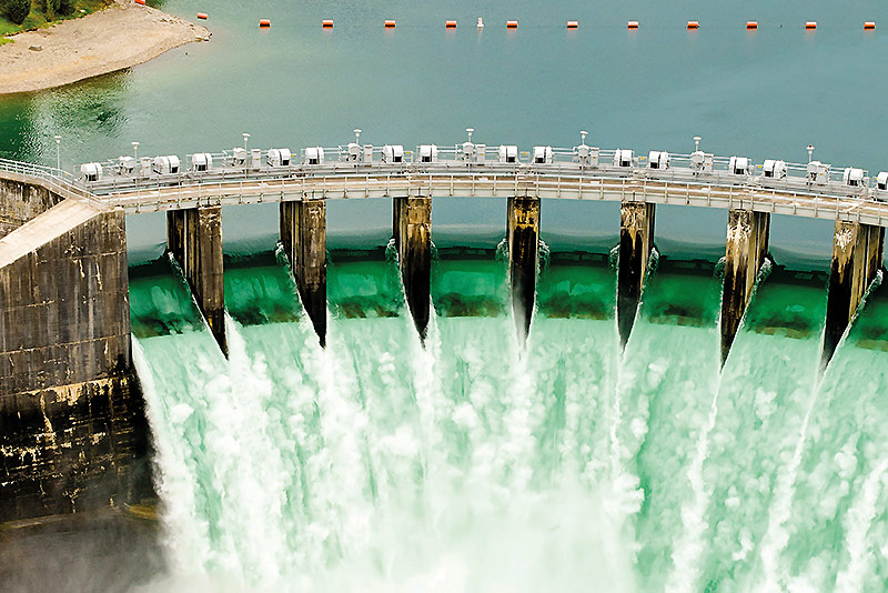 Aerial view of hydro-electric dam spilling water against a backdrop of green countryside