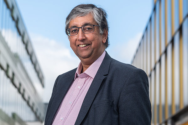 Professor Chas Bountra stands in the foreground against a backdrop of modern buildings at the Old Road Campus, Oxford University