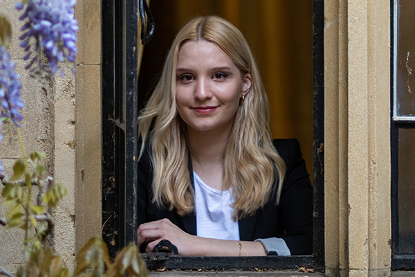 Sophie Forst leaning out of a window of Balliol College