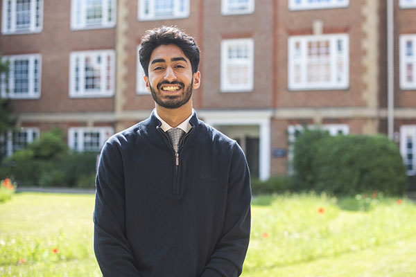 Usama Salamat sitting on a bench in the grounds of Lady Margaret Hall