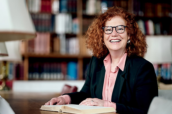 Professor Karen Leeder smiles in the Taylor Institution Library surrounded by books