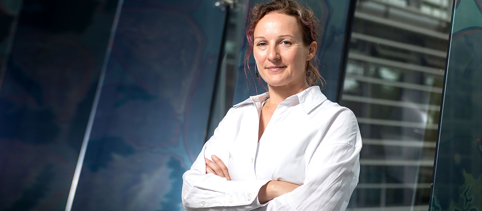 Professor Emma Slack stands with her arms folded against a dark green backdrop