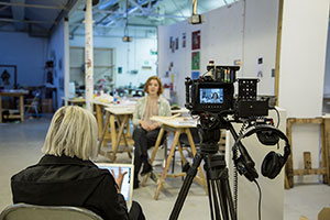 A photo of a student being filmed whilst interviewed in an art workshop