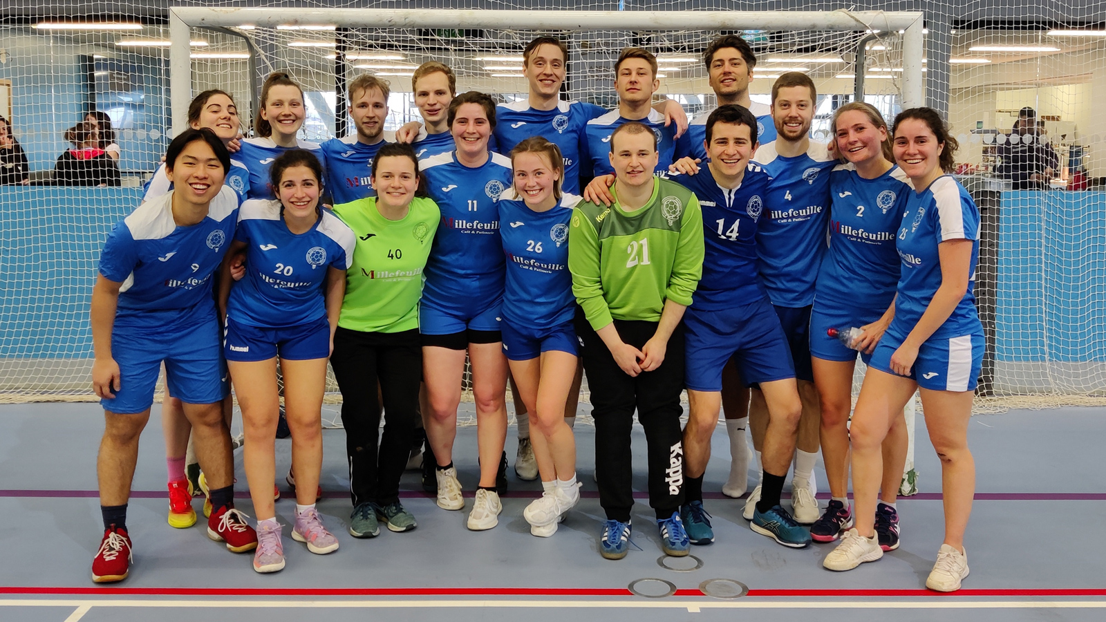 A team of handball players stand in front of a goal