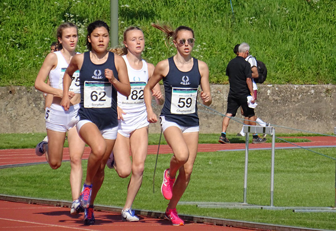 Photo of a close up of four runners racing around a running track