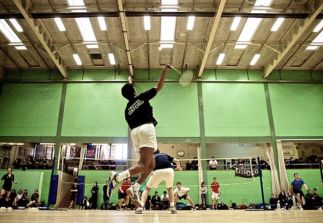 Photo of a badmington player jumping for a smash in a doubles match