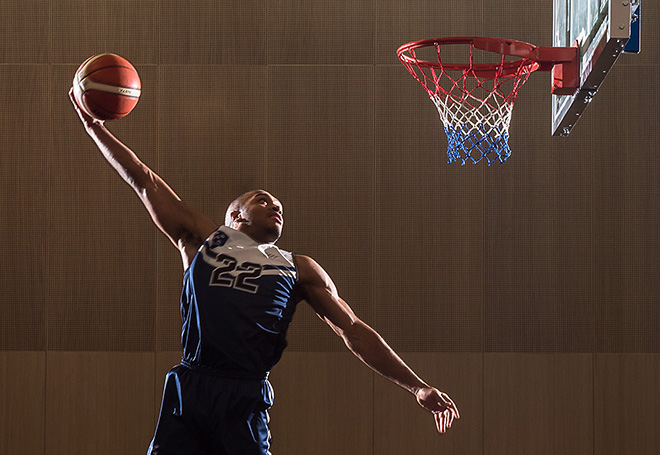 Photo of basketball player performing a windmill slam dunk